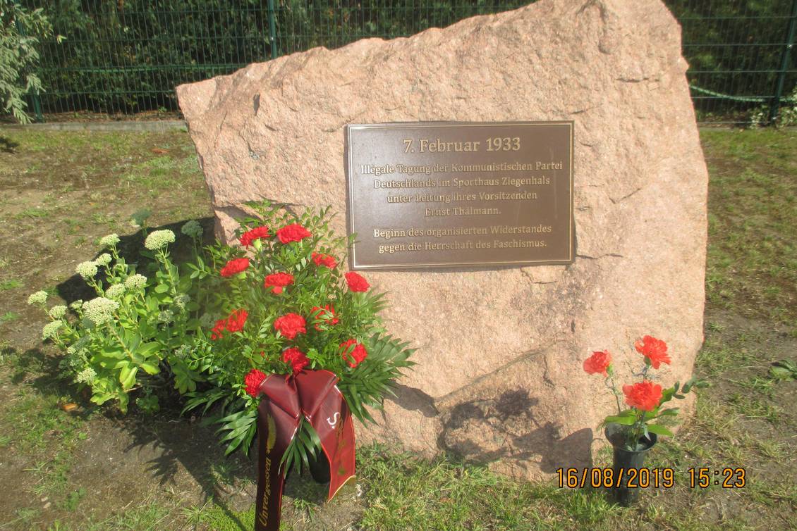 Gedenkstein mit Tafel und Blumengebinde