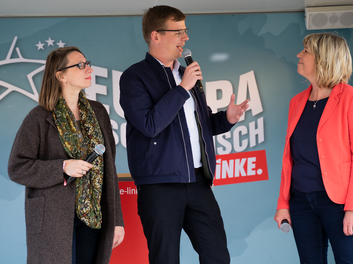 Anja Kreisel, Sebastian Walter und Kathrin Dannenberg stehen mit je einem Mikrofon in den Händen vor einer Wand mit dem Logo der LINKEN