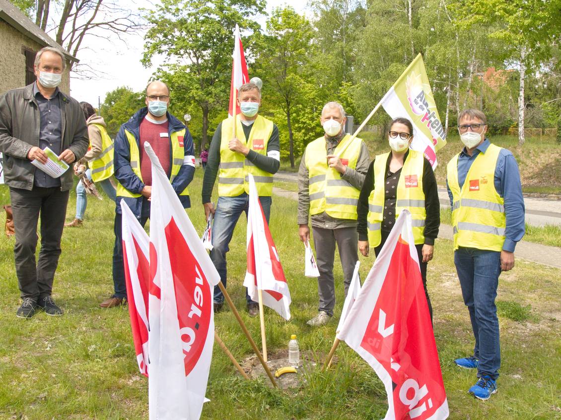 Mehrere Menschen mit Warnwesten und Mund-Nase-Bedeckung, die Fahnen mit Verdi-Logo tragen