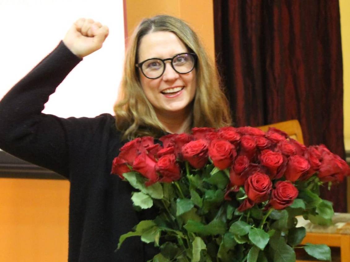Anja Mayer mit einem Strauß roter Rosen, eine Faust in die Luft gestreckt