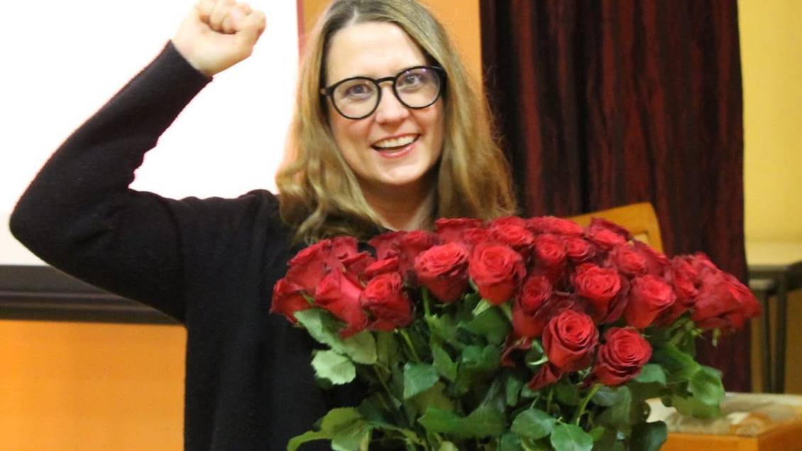 Anja Mayer mit einem Strauß roter Rosen, eine Faust in die Luft gestreckt