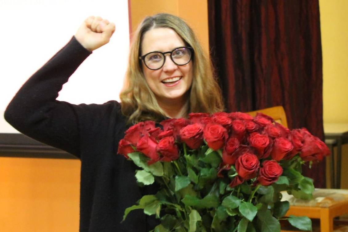 Anja Mayer mit einem Strauß roter Rosen, eine Faust in die Luft gestreckt