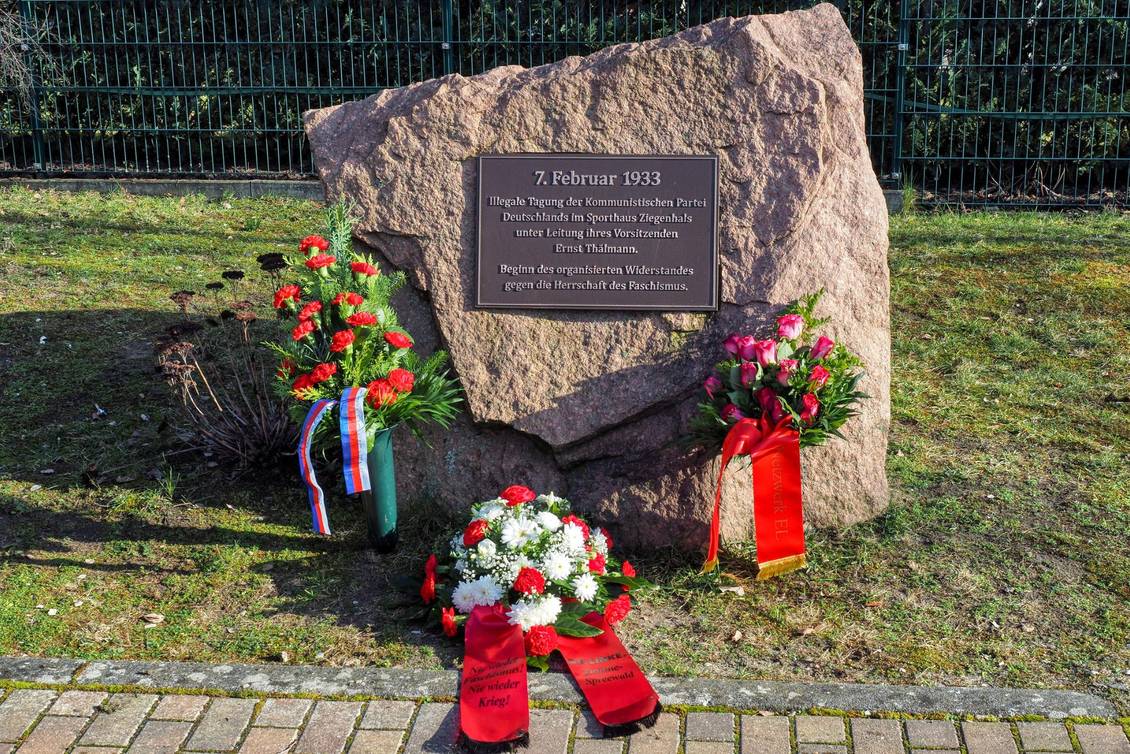 Blumengebinde mit Schleifen am Ernst-Thälmann-Gedenkstein in Ziegenhals