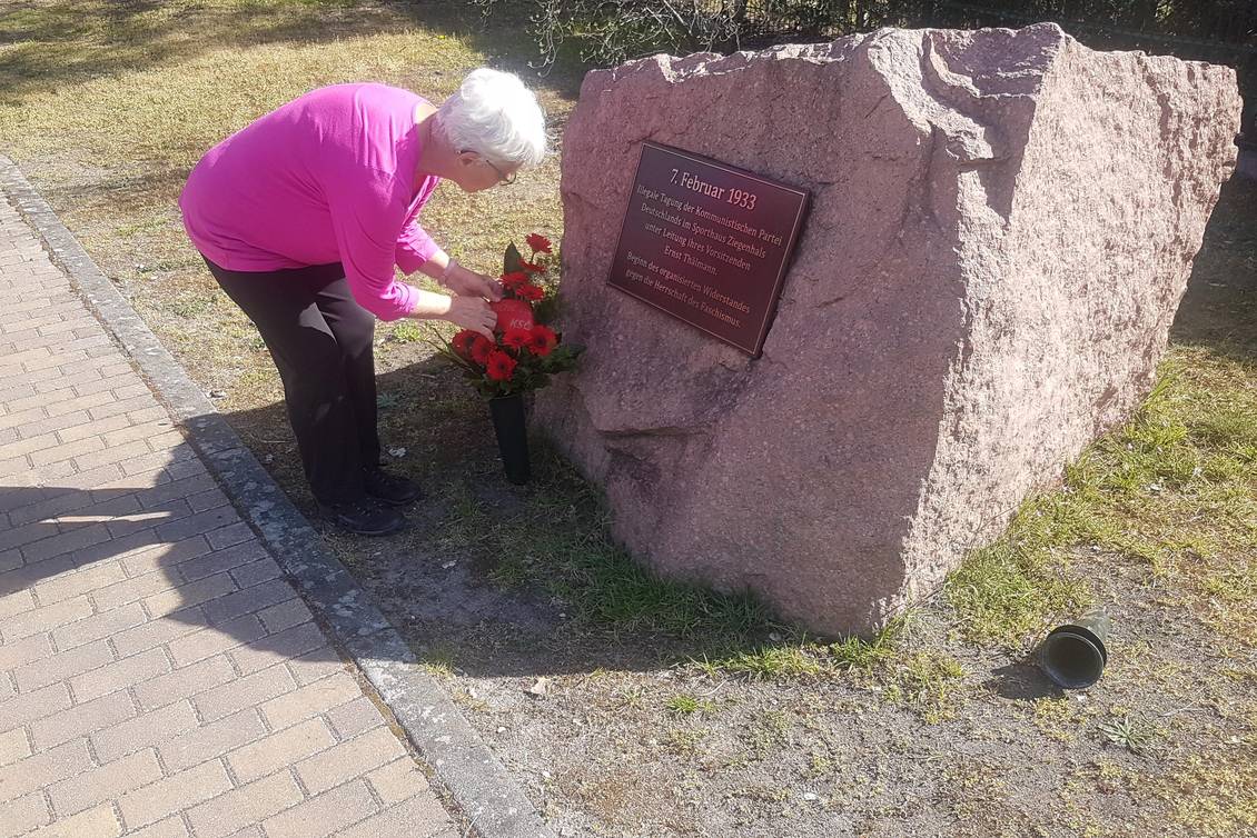 Eine Frau legt einen Blumenstrauß am Ernst-Thälmann-Gedenkstein in Ziegenhals nieder
