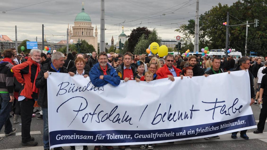 Eine Gruppe Drmonstranten steht hinter einem Transparent mit der Aufschrift "Bündnis Potsdam! bekennt Farbe"