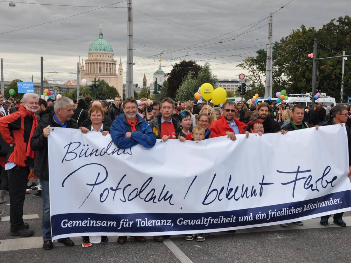 Eine Gruppe Drmonstranten steht hinter einem Transparent mit der Aufschrift "Bündnis Potsdam! bekennt Farbe"