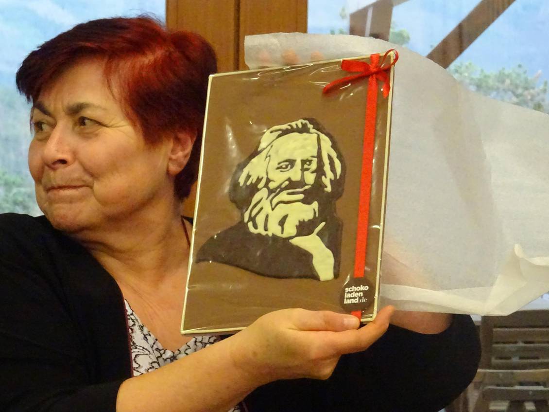Eine Frau hält ein Bildnis von Karl Marx aus Schokolade in die Höhe