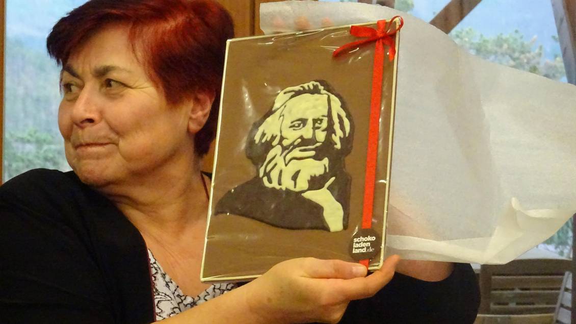 Eine Frau hält ein Bildnis von Karl Marx aus Schokolade in die Höhe