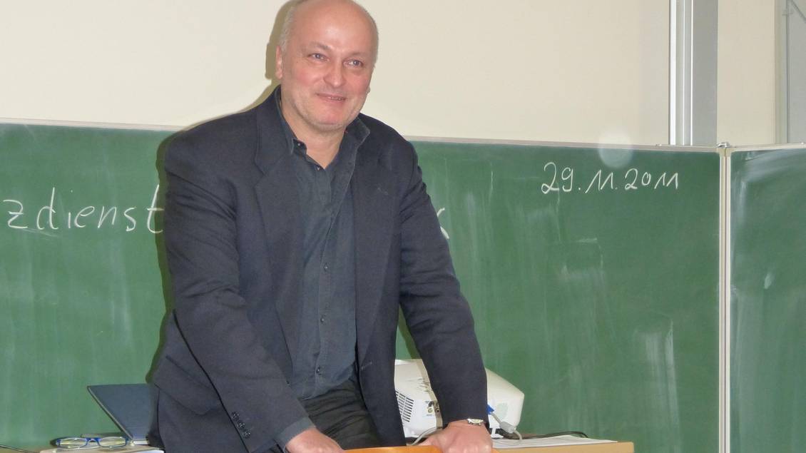 Volkmar Schöneburg steht vor einer Schultafel, die an einer Wand befestigt ist