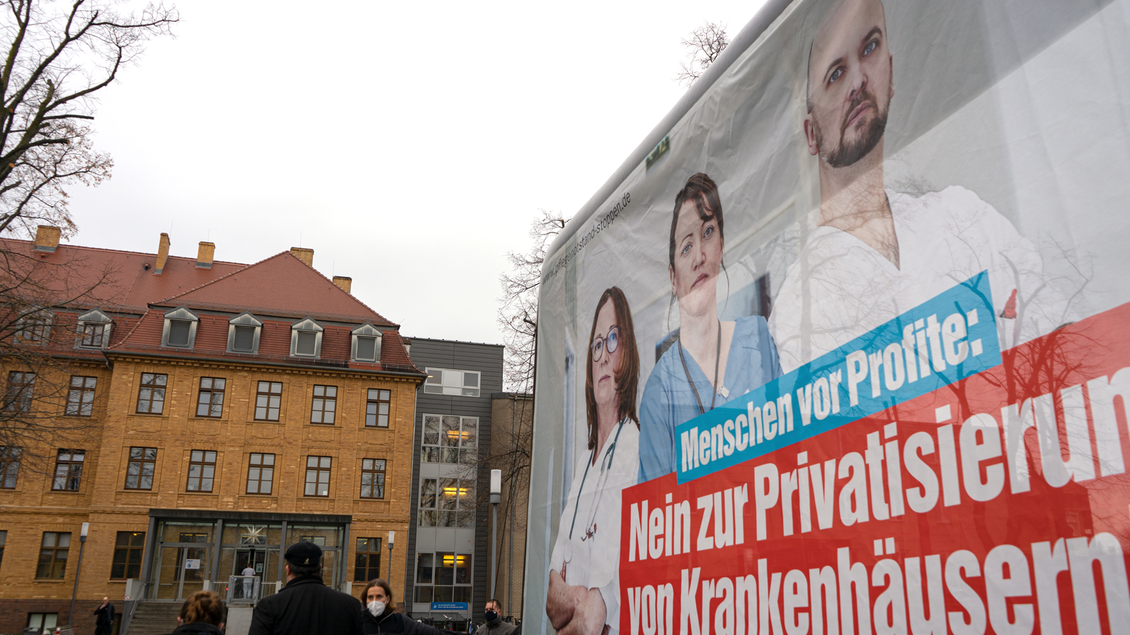 Gebäude des Klinkums in Senftenberg vor dem eine Großfläche steht mit dem Aufdruck "Menschen vor Profit: Nein zur Privatisierung von Krankenhäusern! DIE LINKE."