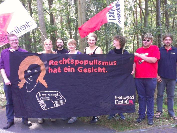 Gruppenfoto mit Fahnen von Linksjugend ['solid] und einem Transparent mit der Aufschrift: "Rechtspopulismus hat ein Gesicht"