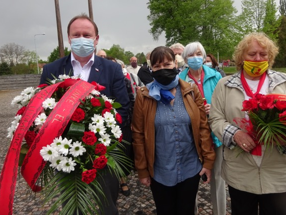 Eine Gruppe von Menschen mit Mundschutz, einige tragen Blumengebinde