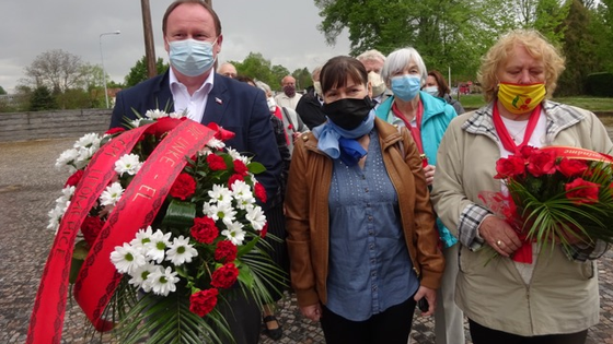 Eine Gruppe von Menschen mit Mundschutz, einige tragen Blumengebinde