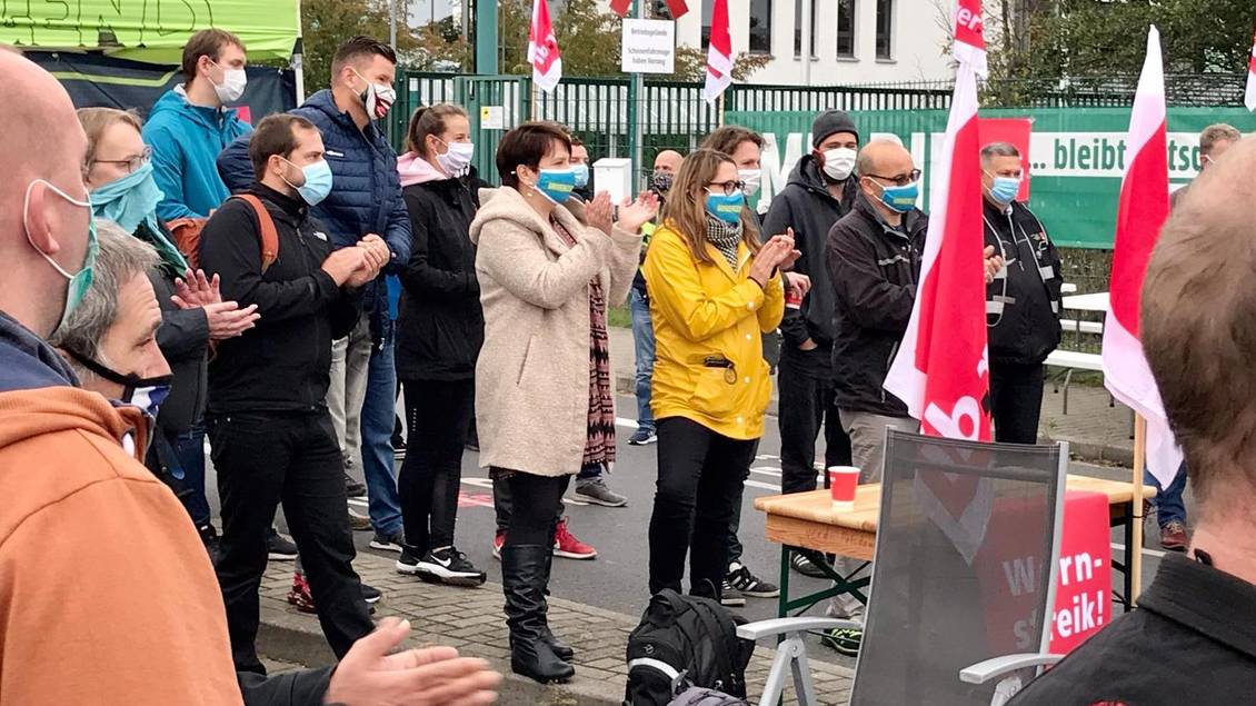 Anja Mayer und Katharina Slanina in einer Versammlung von Streikenden, die alle einen Mund-Nase-Schutz tragen