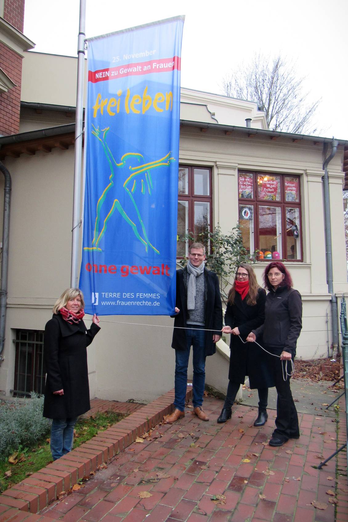 Kathrin Dannenberg, Sebastian Walter, Anja Mayer und Diana Golze hissen gemeinsam die Flagge der Organisation Terre des Femmes mit der Aufschrift "Frei leben – ohne Gewalt"