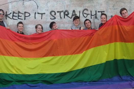 Mitglieder der LAG Queer mit einer überdimensionalen Regenbogen-Flagge