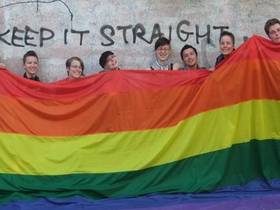 Mitglieder der LAG Queer mit einer überdimensionalen Regenbogen-Flagge
