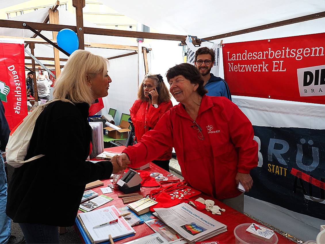 Dagmar Enkelmann steht an einem Infostand, auf dem Zeitungen liegen