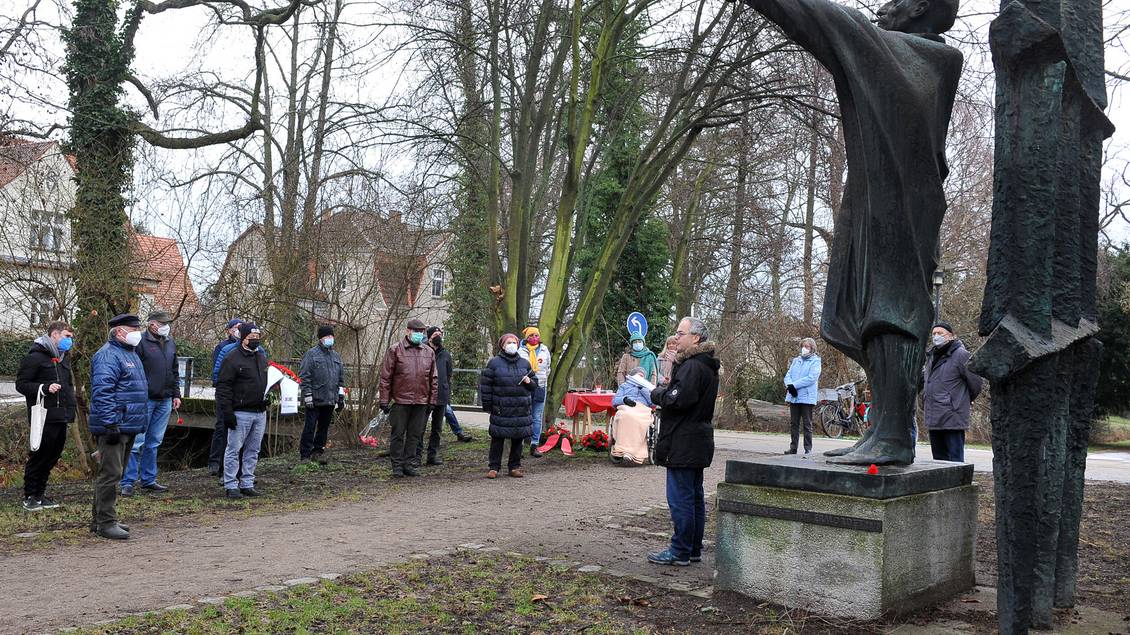 Stefan Wollenberg steht vor dem Karl-Liebknecht-Denkmal in Luckau, eine Gruppe Menschen hört ihm zu