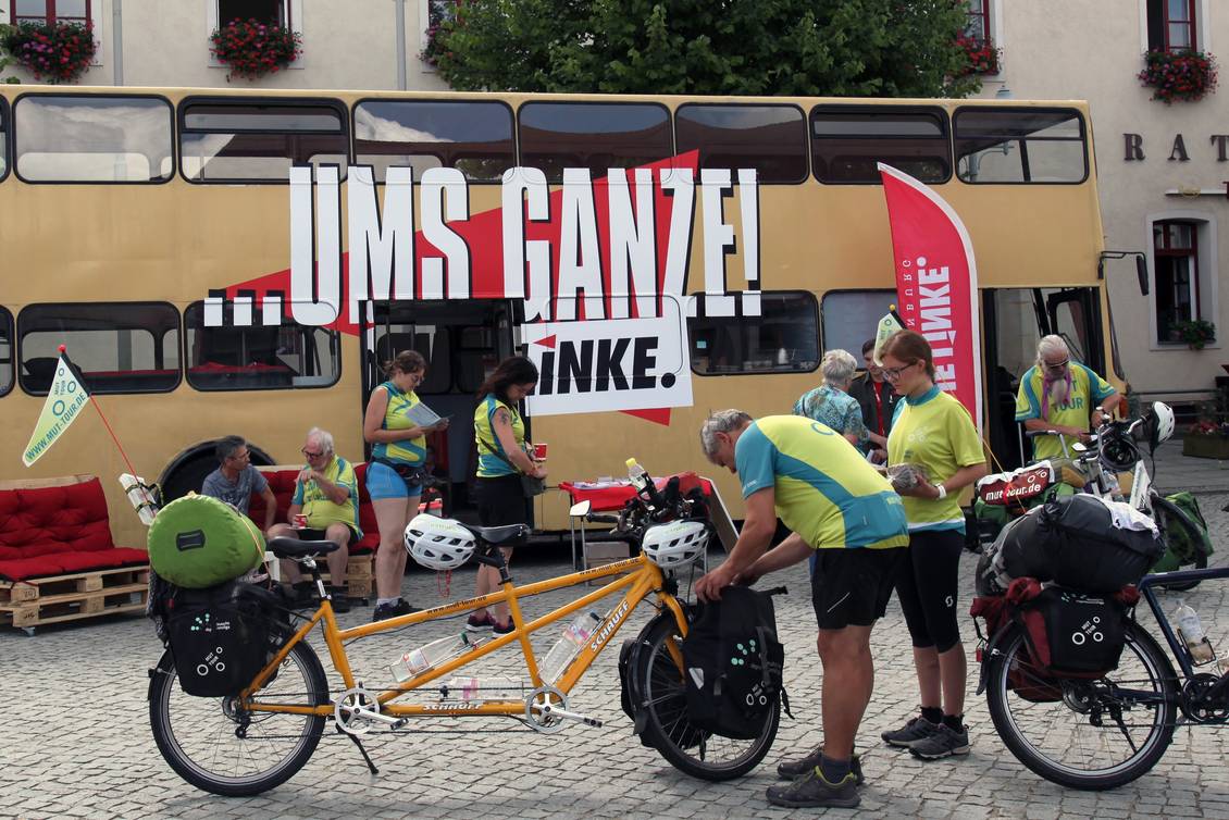 Eine Fahrradfahrer-Gruppe steht vor dem Doppeldecker-Bus am Marktplatz in Herzberg