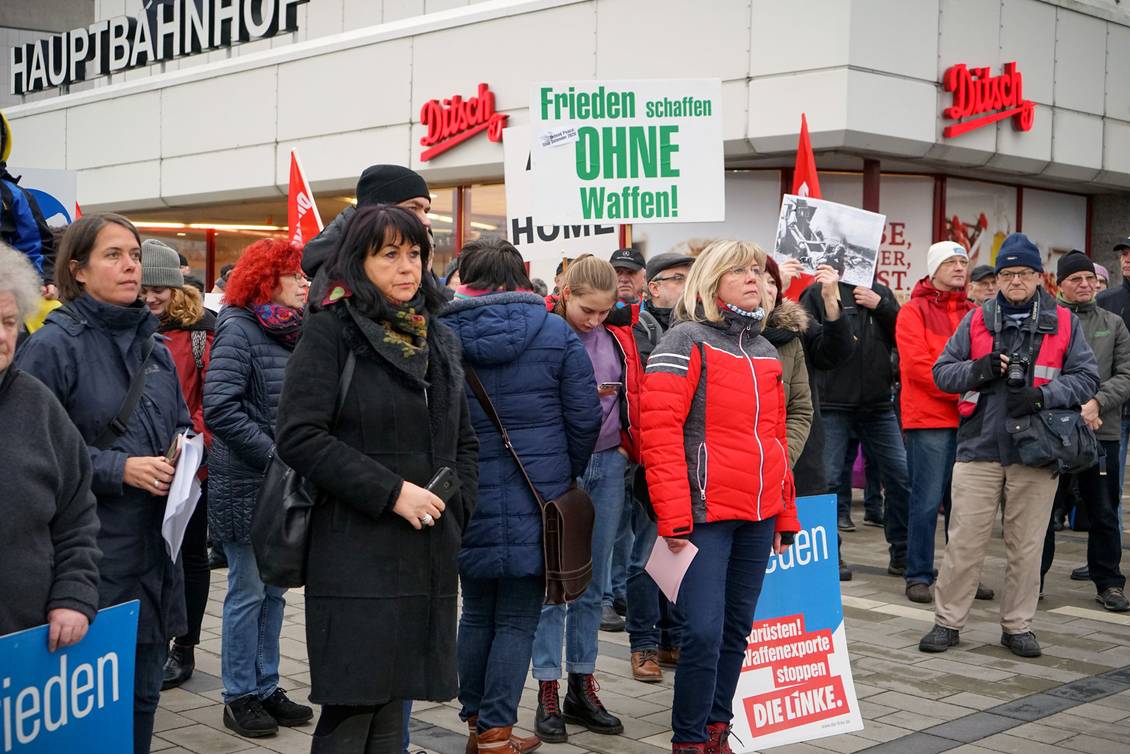 Kathrin Danneneberg steht zwischen Demonstrierenden mit LINKE-Fahnen und Transparenten