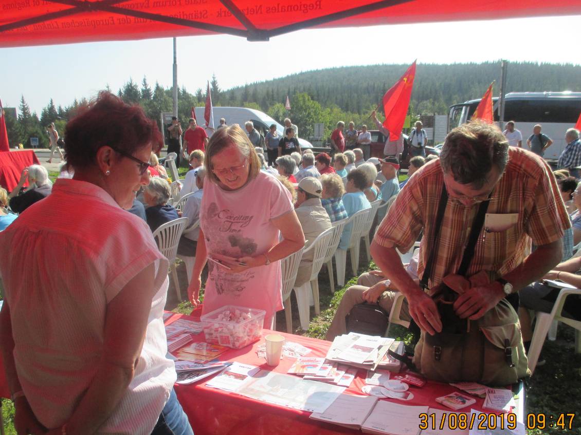 Infostand mit Materialien und Veranstaltungspublikum