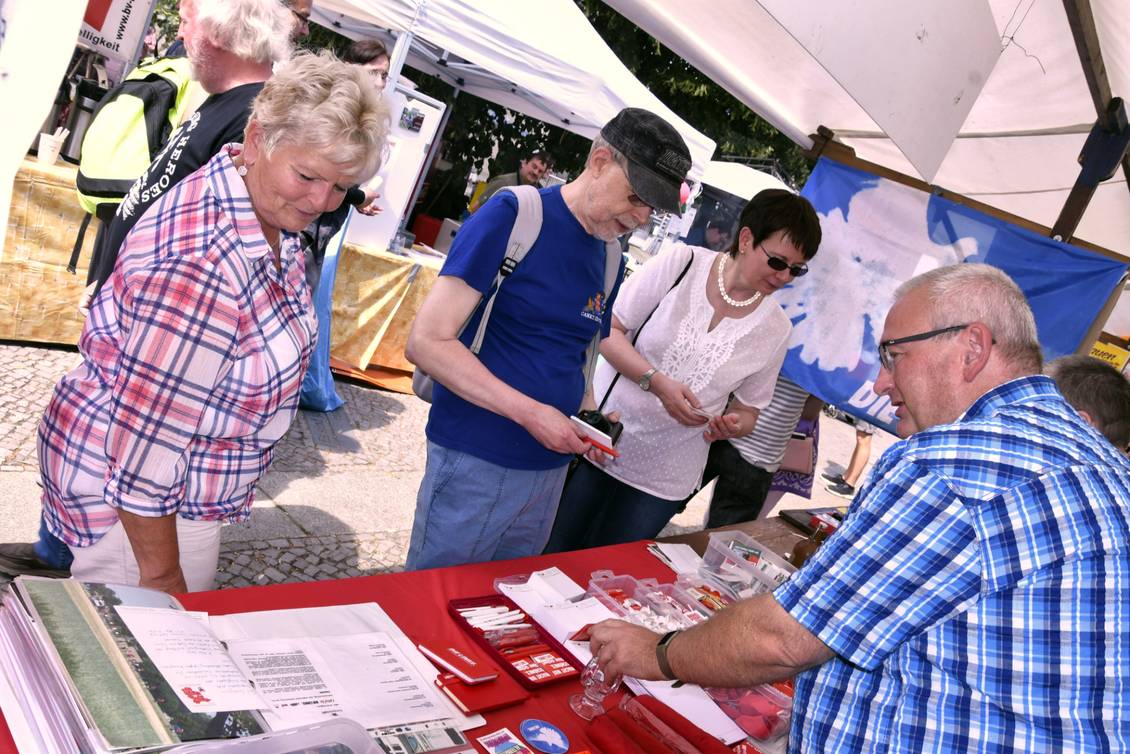 Mehrere Personen stehen an einem Infostand mit Materialien