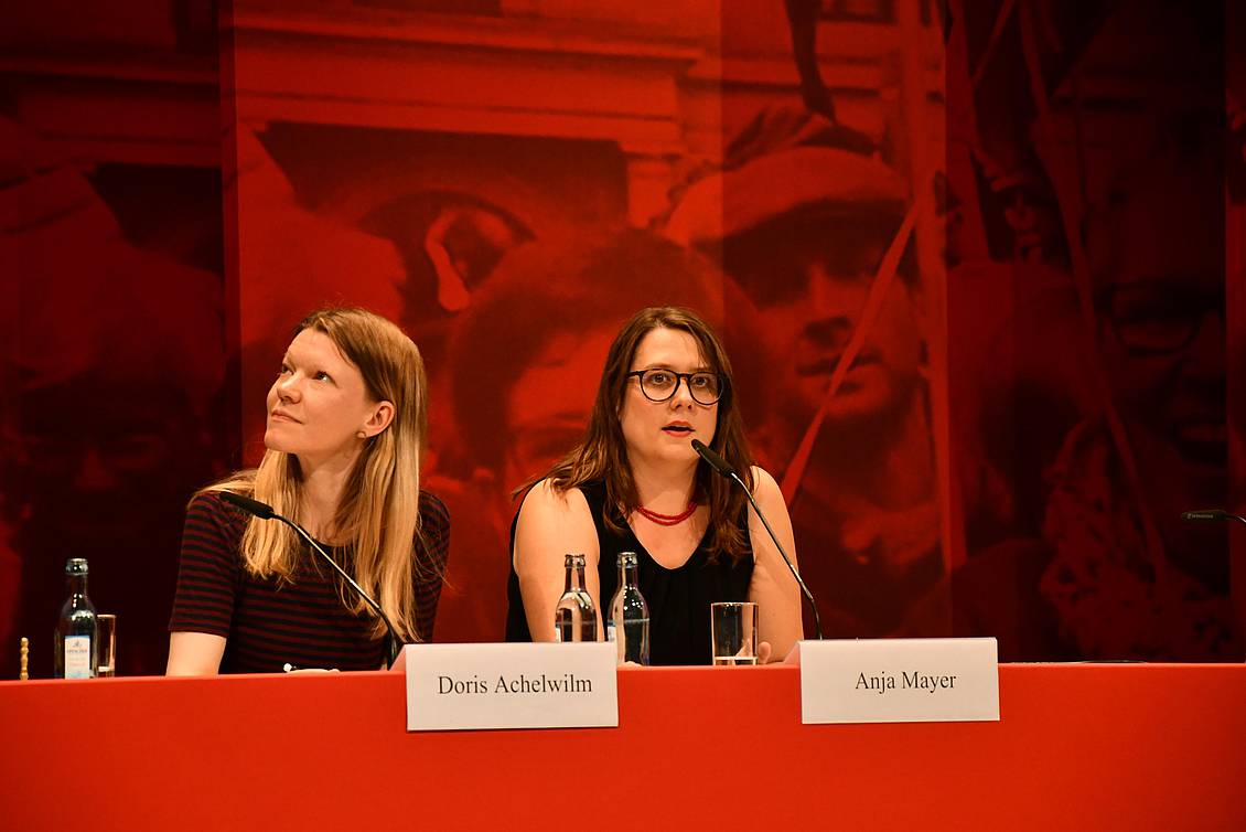 Doris Achelwilm und Anja Mayer sitzen an einem Tisch mit Mikrofon
