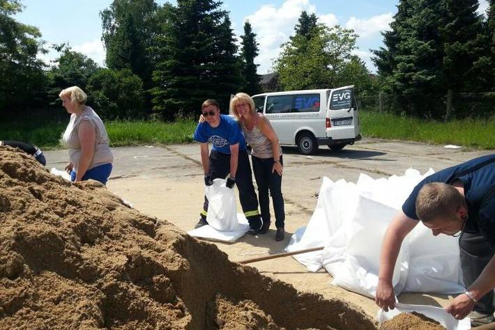 Kornelia Wehlan hat den Arm um einen Helfer gelegt, der einen leeren Sandsack hält