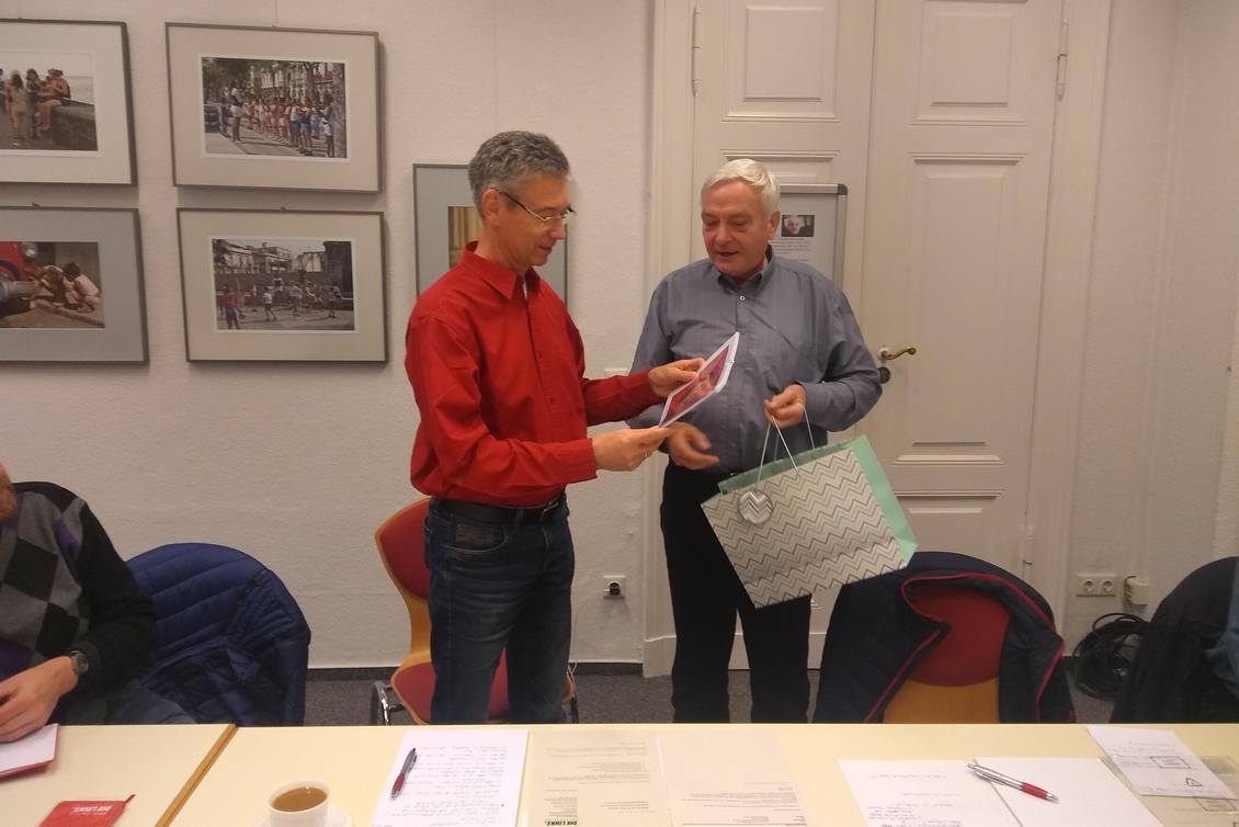 Ein Mann überreicht eine Tüte mit einem Geschenk an Reinhard Frank