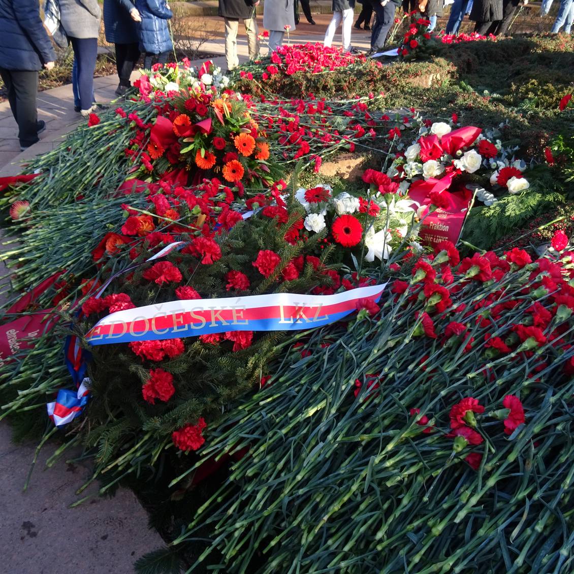 Blumengestecke und Nelken an der zentralen Stele in der Gedenkstätte der Sozialisten in Berlin-Friedrichsfelde