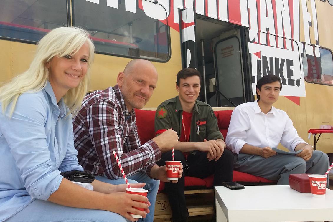 Karsten Eule-Prütz und Aaron Birnbaum sitzen mit weiteren Menschen auf Sofas aus Holzpaletten