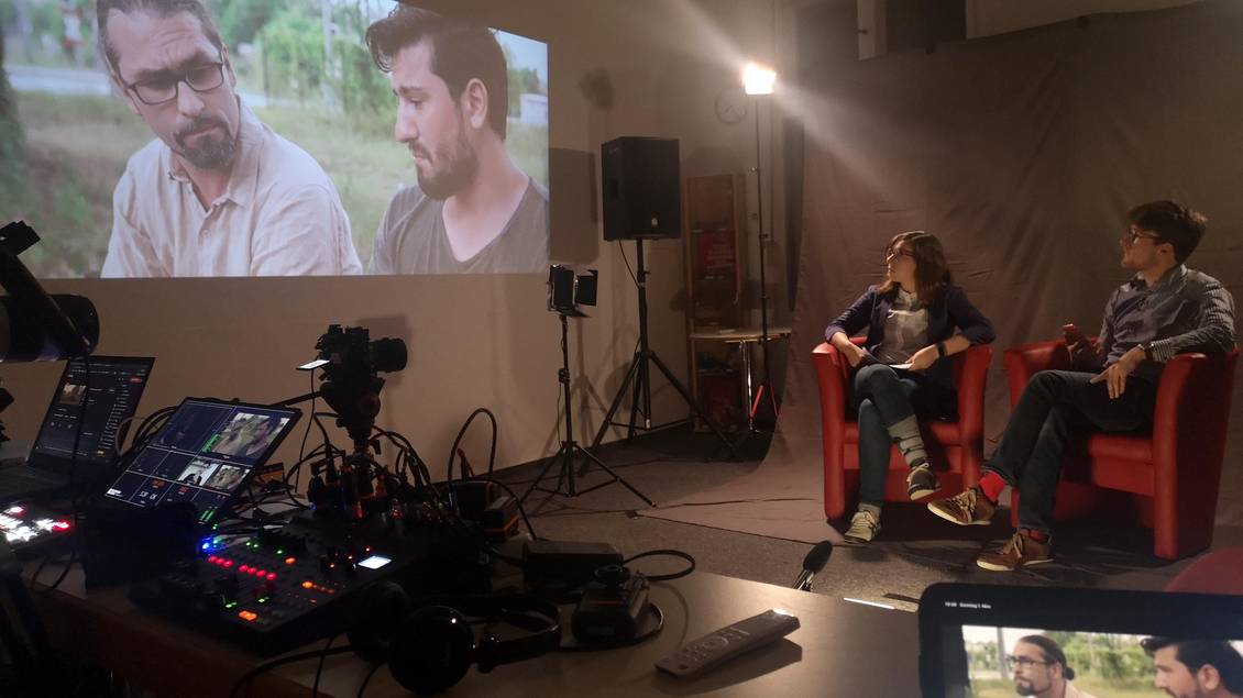 Filmset mit Scheinwerfern, Kamera und dem Film, der per Beamer an die Wand geworfen wird