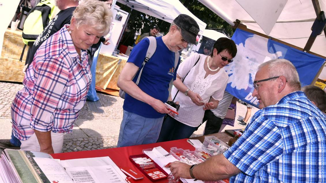 Mehrere Personen stehen an einem Infostand mit Materialien