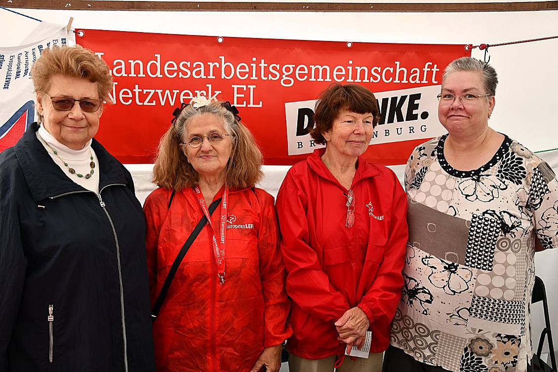 Vier Frauen stehen vor einem roten Banner