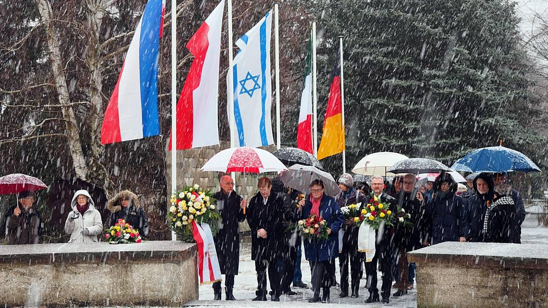 Teilnehmer*innen mit Regenschirmen und Blumengestecken