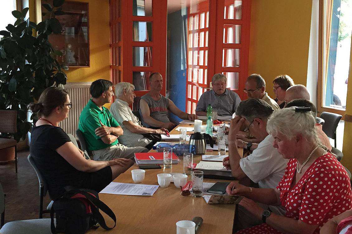 Anja Mayer und eine Gruppe Menschen sitzen an einem langen Tisch