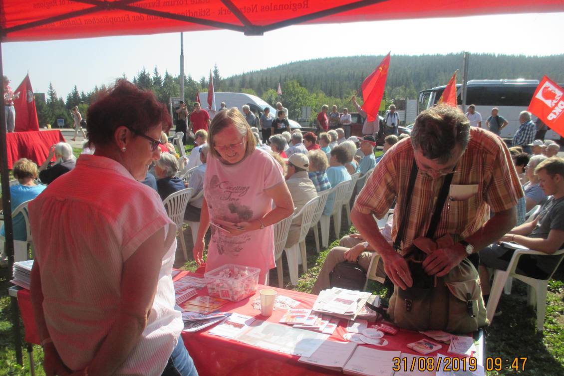 Infostand mit Materialien und Veranstaltungspublikum