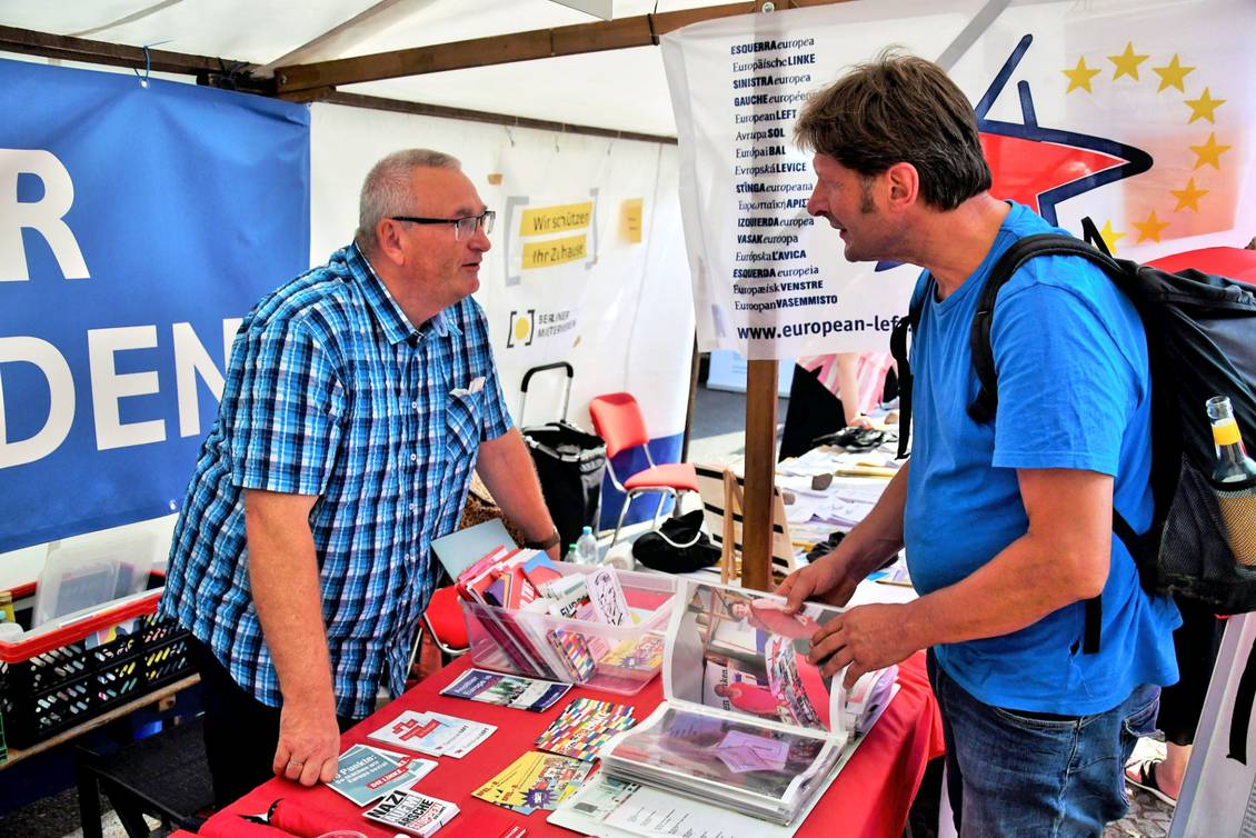 Zwei Männer stehen an einem Infostand mit Materialien