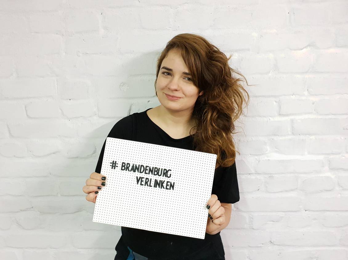 Claudia Sprengel hält ein Schild, auf dem "Brandenburg verlinken" steht
