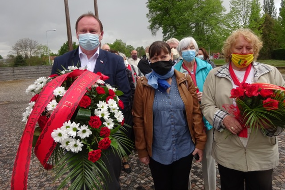 Eine Gruppe von Menschen mit Mundschutz, einige tragen Blumengebinde