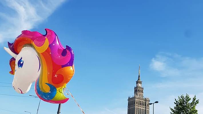 Menschen mit Regenbogen-Fahnen und einem Einhorn-Luftballon vor dem Kulturpalast in Warschau