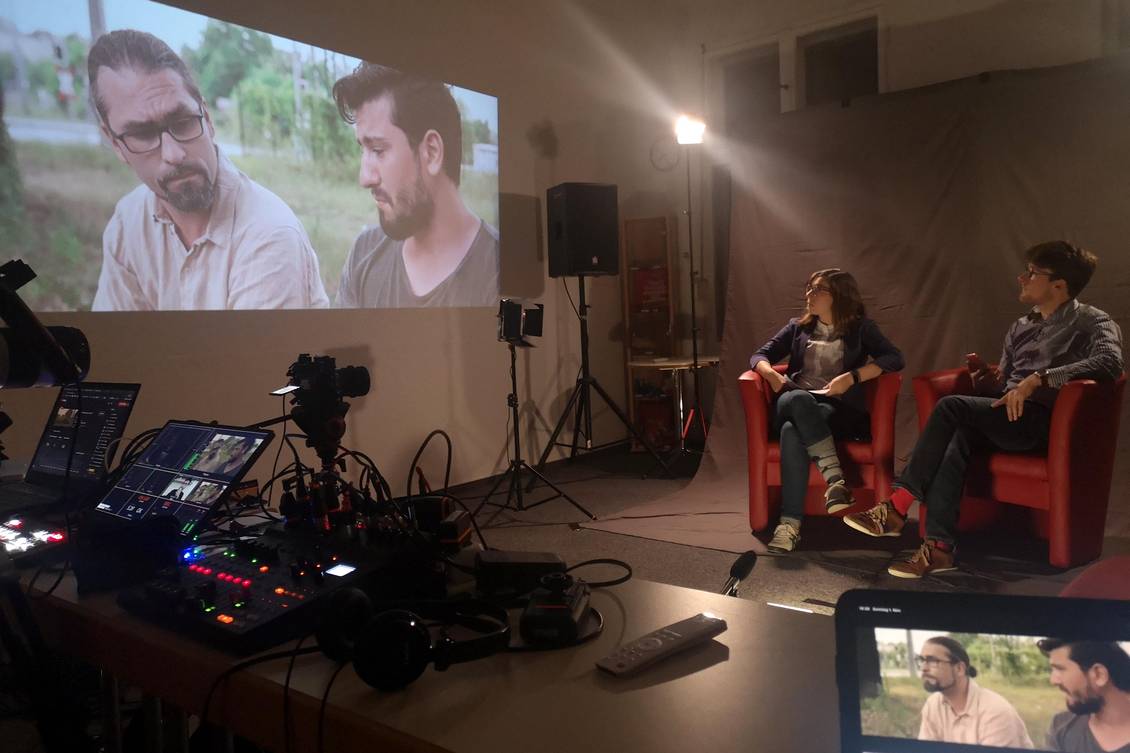Filmset mit Scheinwerfern, Kamera und dem Film, der per Beamer an die Wand geworfen wird