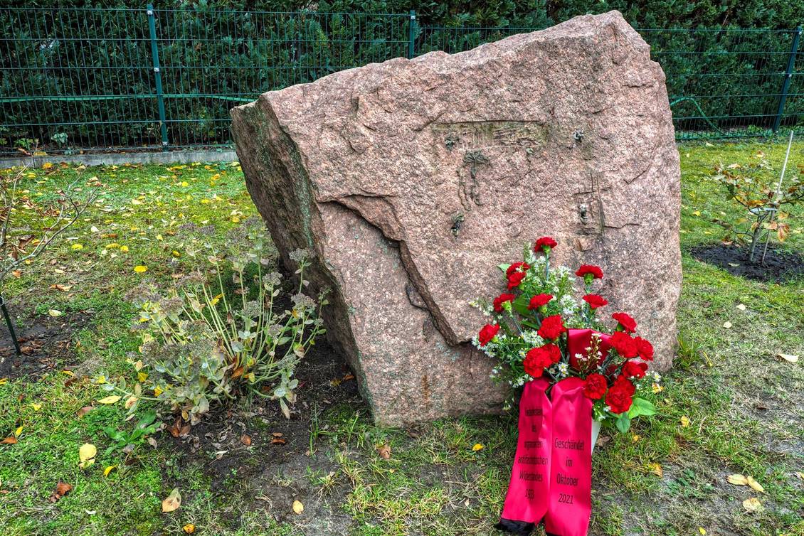 Gedenkstein mit einem Blumengebinde mit Schleife