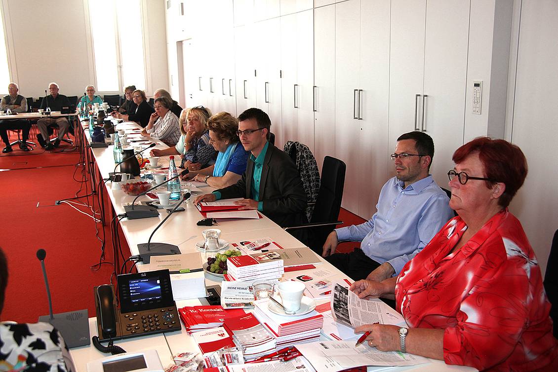 Konferenz in einem Besprechunsgraum mit Getränken auf den Tischen, an einem Tisch sitzt Margitta Mächtig