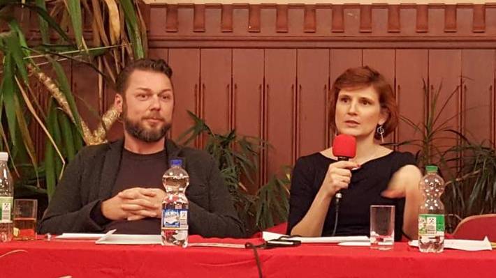 Ringo Jünigk und Katja Kipping mit Mikrofon in der Hand sitzen an einem Tisch mit roter Tischdecke